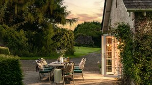 An outdoor patio with a table and chairs, surrounded by greenery and a stone wall. - Auchengashell - sleeps 8 guests  in 4 bedrooms (Kirkcudbright)