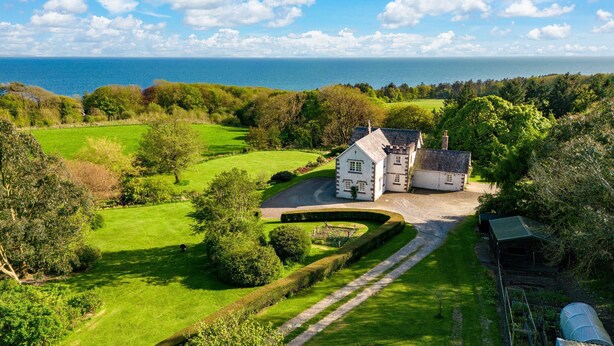 A large white house with a driveway, surrounded by lush green lawns and trees, overlooking a body of water. - Auchengashell - sleeps 8 guests  in 4 bedrooms (Kirkcudbright)
