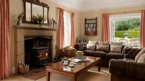 A cozy living room with a fireplace, leather sofa, and a bookshelf. - Auchengashell - sleeps 8 guests  in 4 bedrooms (Kirkcudbright)