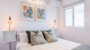 A modern bedroom with a bed, two wall-mounted lamps, and two framed artworks. - Casa Checha Charming Penthouse With Breathtaking Views (Candelaria)