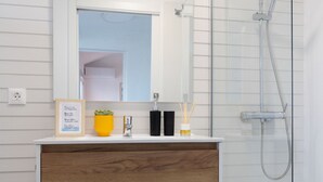 A modern bathroom with a wooden vanity, a glass shower enclosure, and a mirror above the vanity. - Casa Checha Charming Penthouse With Breathtaking Views (Candelaria)