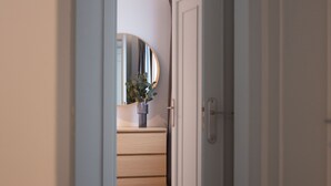 Un pasillo que conduce a una habitación con un aparador de madera y un espejo.