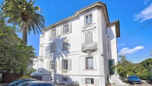 A white multi-story building with balconies, parked cars, and palm trees. - Upstays Studio Top Floor Sea View Cannes (Cannes)