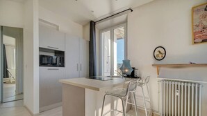 A modern kitchen with a central island, bar stools, a microwave, and a radiator. - Upstays Studio Top Floor Sea View Cannes (Cannes)