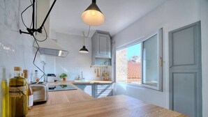 A modern kitchen with a wooden countertop, built-in cabinets, and a window providing natural light. - Upstays Banane Terrace 30m² Studio (Cannes)