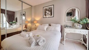 Ein Hotelzimmer mit einem großen Bett, einem Nachttisch, einem Spiegel und einem an der Wand hängenden Bild.