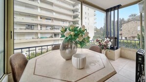 Ein Balkon mit Tisch, zwei Vasen und Blick auf ein mehrstöckiges Gebäude.