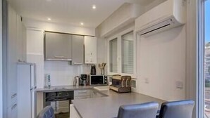 Une cuisine moderne avec des meubles blancs, un îlot central et des tabourets de bar.