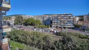 Un immeuble à plusieurs étages doté de balcons, d’un parking et surplombant un ciel bleu dégagé.