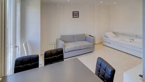 Un salon moderne avec un canapé gris, un canapé blanc, une table à manger avec des chaises et une petite table d’appoint.