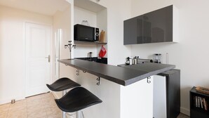 Een moderne keuken met een centraal eiland, barkrukken, een magnetron en een groot zwart kast.