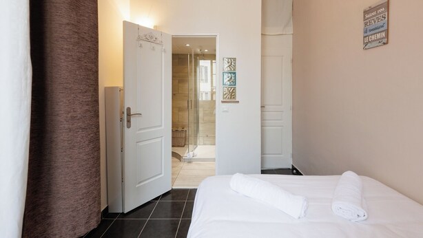 Een hotelkamer met een bed, een douche en een deur naar een andere kamer.