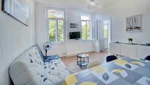 Una habitación moderna y bien iluminada con un sofá, una mesa de comedor y un televisor.