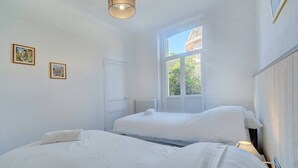 Un dormitorio con dos camas, una ventana, una puerta y una lámpara en el techo.