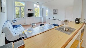 Una sala moderna con un sofá, una mesa de comedor y una zona de cocina.
