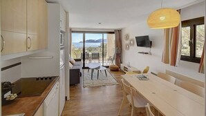 A modern kitchen with a dining area, a TV mounted on the wall, and a view of the sea. - Upstays Terrace Pool Parking 40m² Apartment (Cannes)