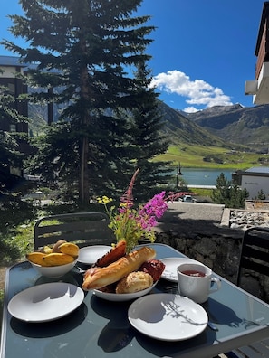A table with a meal, a flower arrangement, and a scenic mountain view. - Upstays Cosy Family Ski Near Slopes and Lake (Tignes)