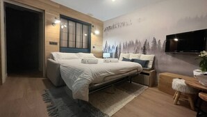 A modern bedroom with a bed, bedside tables, a TV, and a mural. - Upstays Cosy Family Ski Near Slopes and Lake (Tignes)