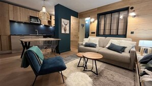 A modern living room with a sofa, two small round tables, a blue chair, and a fluffy rug. - Upstays Cosy Family Ski Near Slopes and Lake (Tignes)