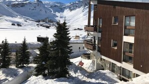 A modern building with a wooden facade, surrounded by snow-covered mountains and a clear sky. - Upstays Cosy Family Ski Near Slopes and Lake (Tignes)