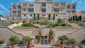 A multi-story hotel with a symmetrical facade, balconies, and a central entrance.
