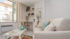 A living room with a sofa, a coffee table, a chair, and a bookshelf. - Upstays Palais Center 38m² Studio (Cannes)