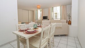 A dining area with a table set for four, a sofa, and a television in the background. - Upstays Palais Center 38m² Studio (Cannes)