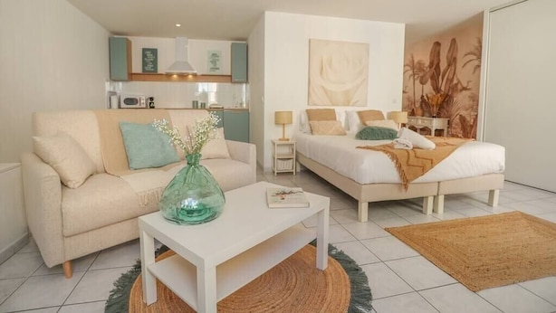 A modern, well-lit living room with a sofa, coffee table, and a bed with a headboard. - Upstays Palais Center 38m² Studio (Cannes)