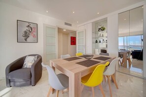Un comedor moderno con una mesa de madera, varias sillas y un separador de vidrio.