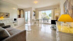 A modern living room with a sofa, a TV, and a dining area with a table and chairs. - Upstays Sea View 50m² Apartment Bocca (Cannes)