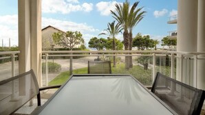 A balcony with a table and chairs, overlooking a parking area and palm trees. - Upstays Sea View 50m² Apartment Bocca (Cannes)