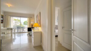 A bright, modern hotel room with a clean, minimalist design, featuring a dining area, a bed, and a large window offering a view of the outdoors. - Upstays Sea View 50m² Apartment Bocca (Cannes)