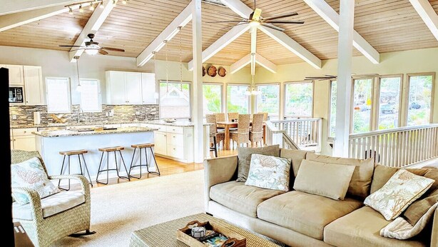 A spacious living area with a large sofa, a coffee table, and a kitchen area with a bar stool. - Roof deck views, hot tub, big kitchen, 3200sf, BBQ (Kailua-Kona)