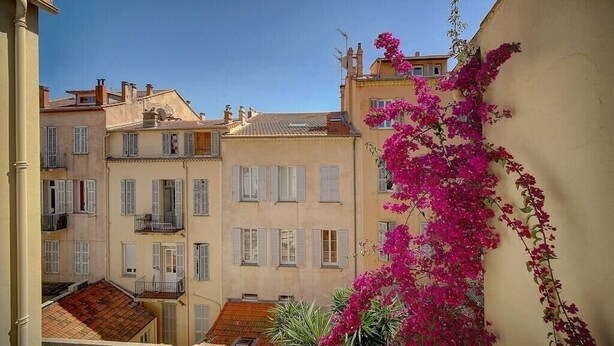 A narrow street with buildings on either side, featuring balconies and shutters. - Upstays République 67m² Apartment (Cannes)