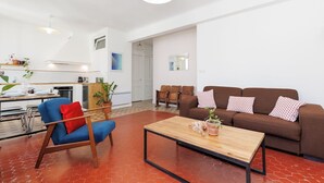 A modern living room with a brown sofa, a blue chair, and a wooden coffee table. - Upstays République 67m² Apartment (Cannes)