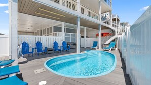 A pool area with blue chairs and a pool on a wooden deck.