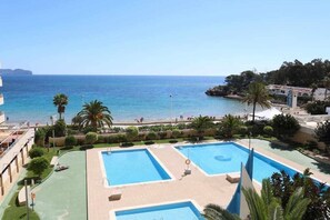 A resort with two large swimming pools, a beach, and a view of the sea.