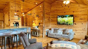 A log cabin interior with a bar area, seating, and a TV. - Secluded Mountain Cabin: Hot Tub & Spectacular (Ruidoso)