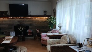 A cozy living room with a fireplace, a television mounted on the wall, and a comfortable seating area with a patterned armchair and a sofa. - Work crews welcome! near the I-71/Rt 13 and I-71/Rt 39  easy access to Mansfield (Mansfield)