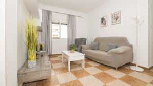 En moderne stue med en beige sofa, et hvidt sofabord og et ternet gulv.