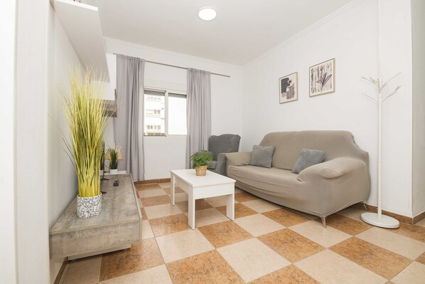 A modern living room with a beige sofa, a white coffee table, and a checkered floor.