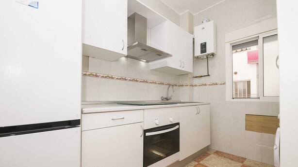 Una cocina con armarios blancos, horno de acero inoxidable y salpicadero de azulejos.