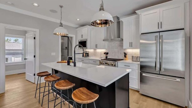 Una cocina moderna con una isla central, electrodomésticos de acero inoxidable e iluminación colgante.