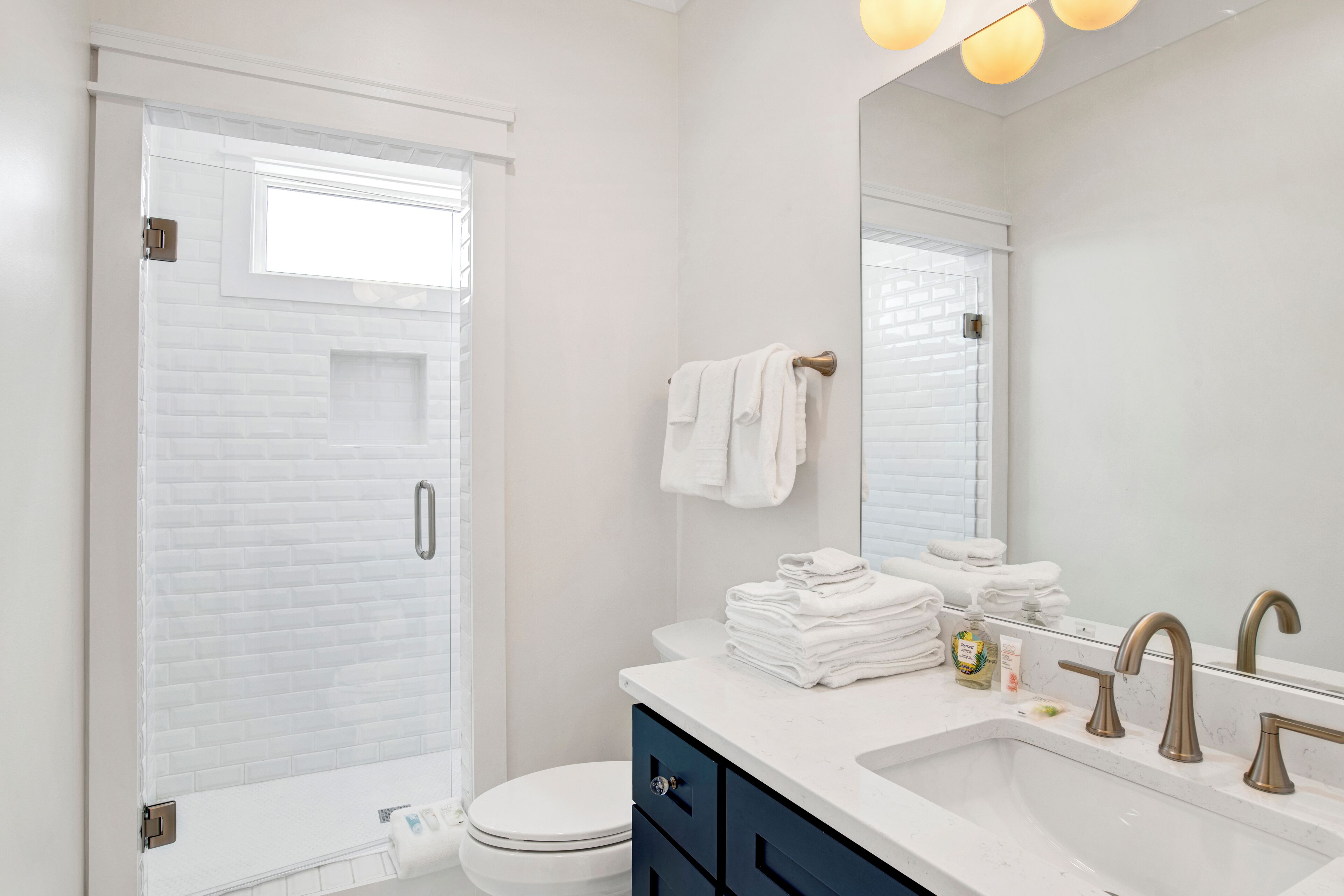 A modern bathroom with a white brick wall, a white toilet, a sink with a mirror, and a towel rack.