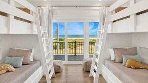 Ein Schlafzimmer mit Meerblick, ein Balkon mit Geländer und ein Bett mit Kissen und Stofftier.