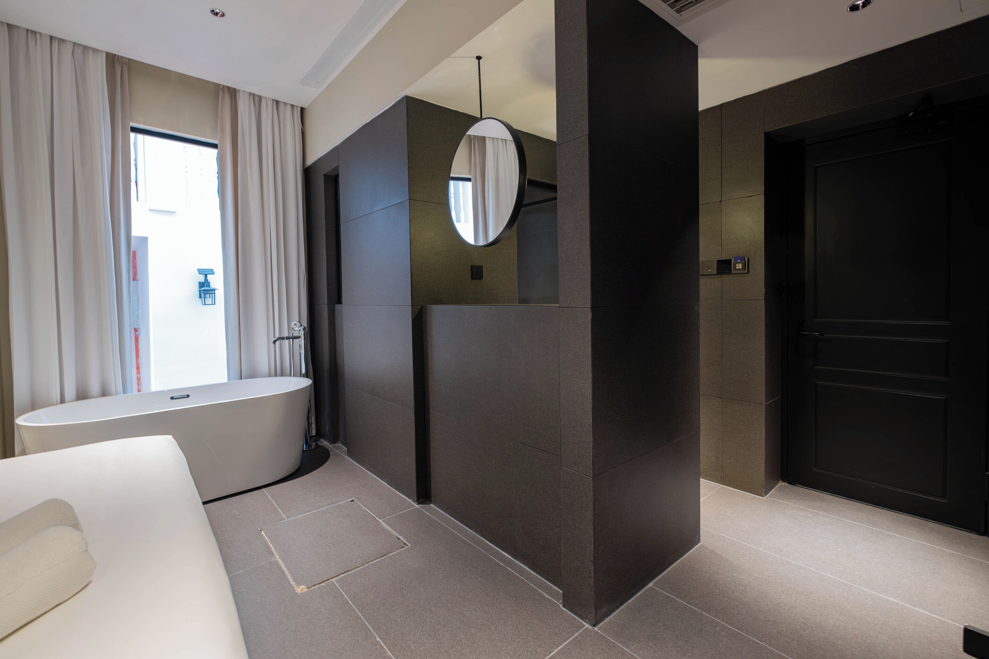 Un baño moderno con bañera, un espejo grande y una puerta oscura.