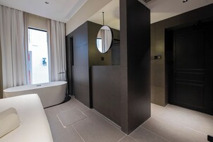 Un baño moderno con bañera, un espejo grande y una puerta oscura.