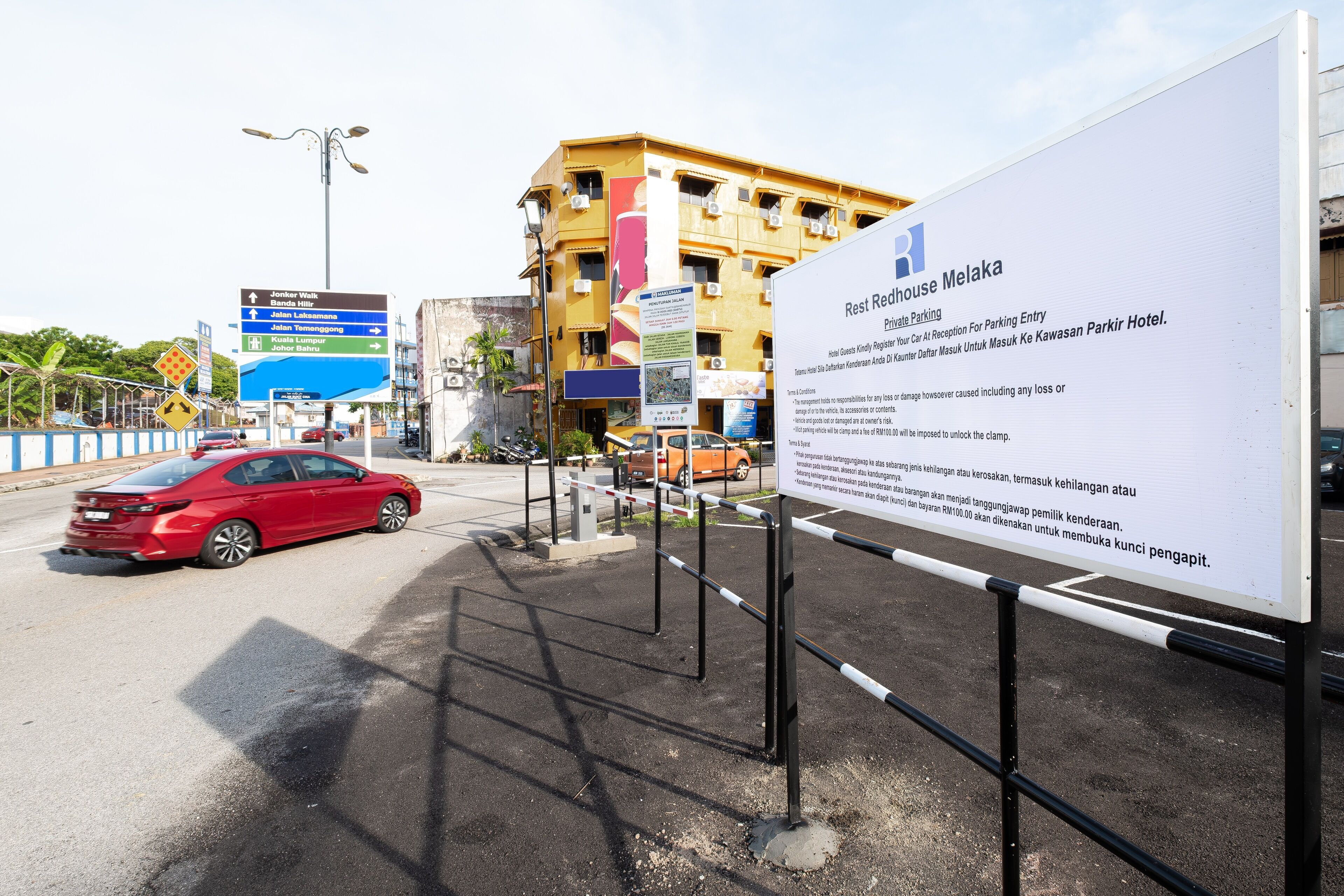 A sign for Resthouse Melaka with directions to various locations.