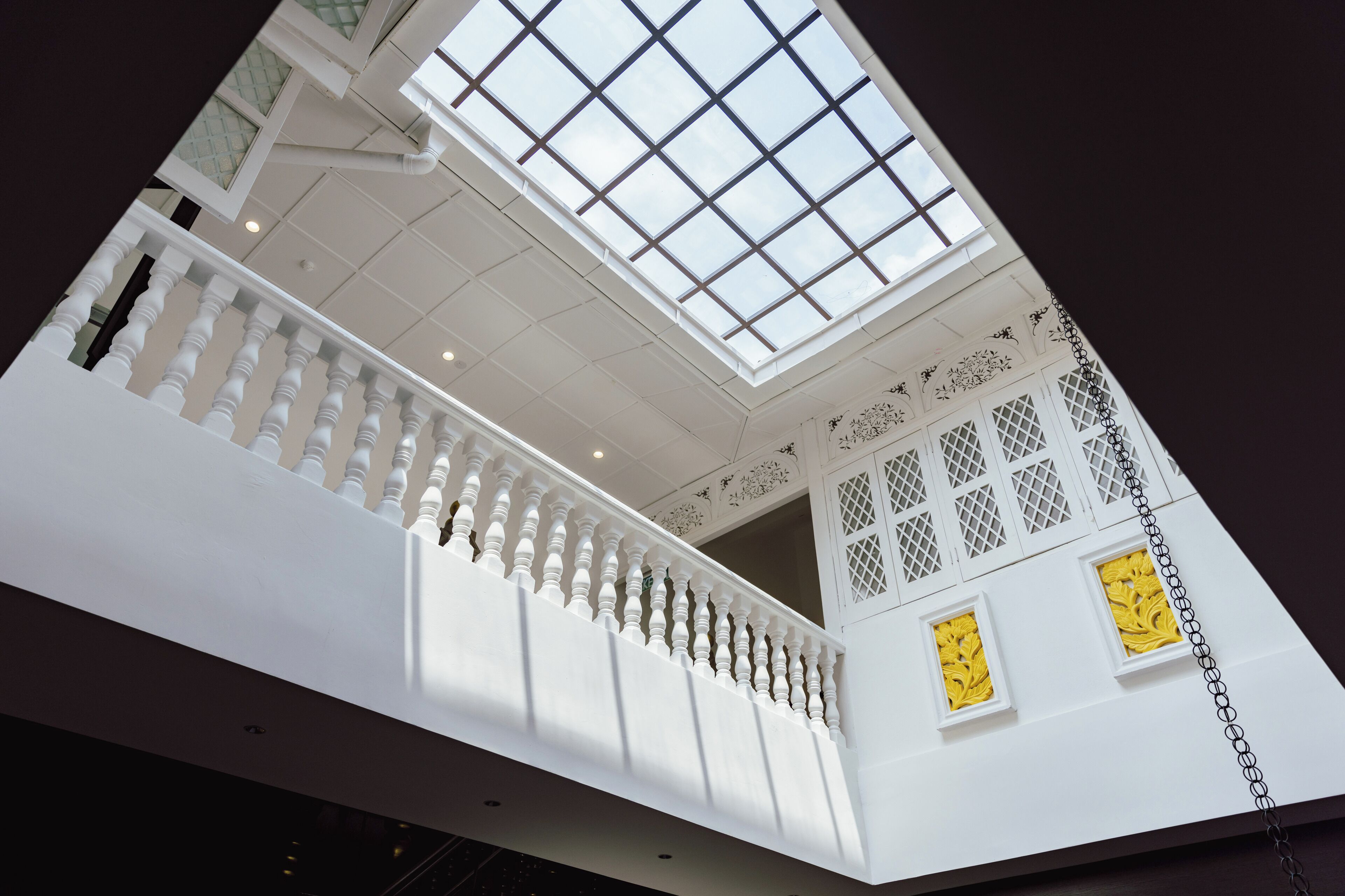 A high-ceilinged interior with a white balustrade and a skylight.