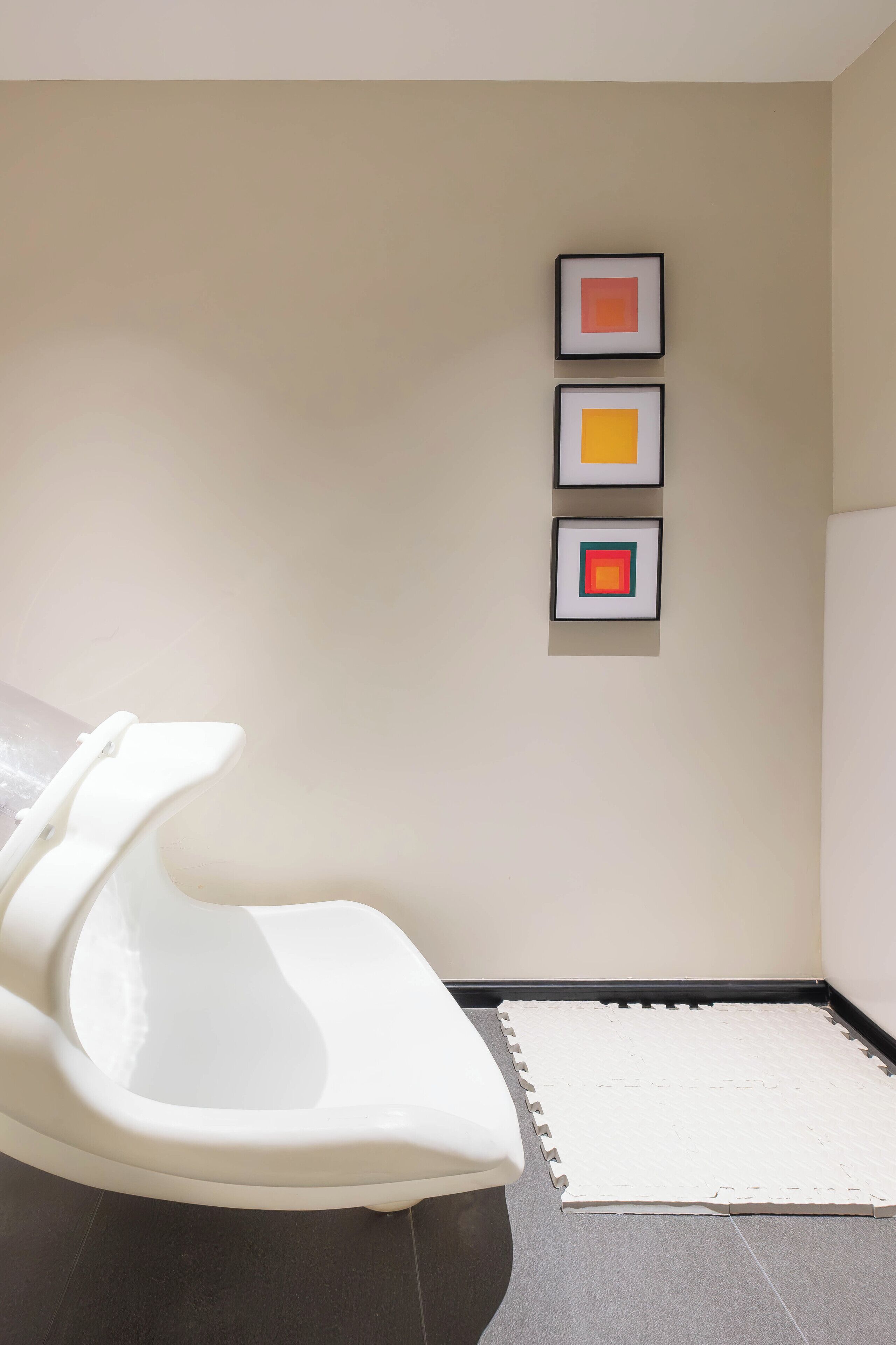 Ein modernes Badezimmer mit einer weißen Badewanne, einer weißen Toilette und einer weißen Duschkabine. An der Wand hängen drei gerahmte Kunstwerke.